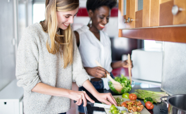 Two women preparing a meal in a brightly lit kitchen