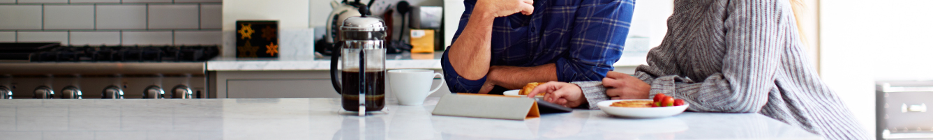 a couple browsing the internet while having breakfast in the kitchen