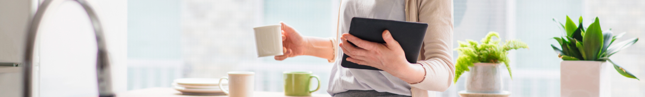 A woman holding a tablet while having coffee